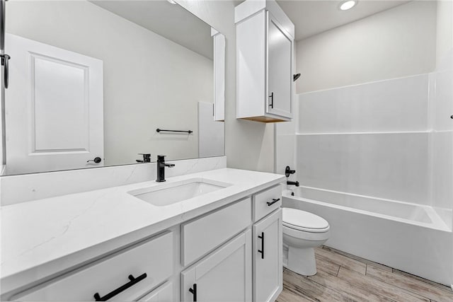 bathroom with washtub / shower combination, toilet, vanity, and wood finished floors