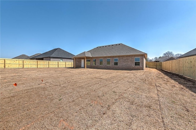 back of property with a fenced backyard and brick siding