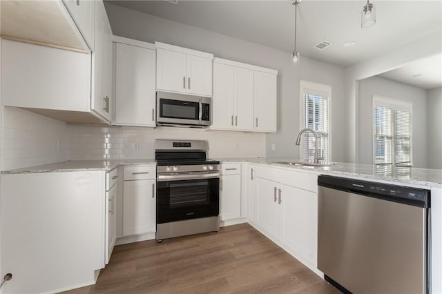 kitchen with kitchen peninsula, stainless steel appliances, pendant lighting, and white cabinets