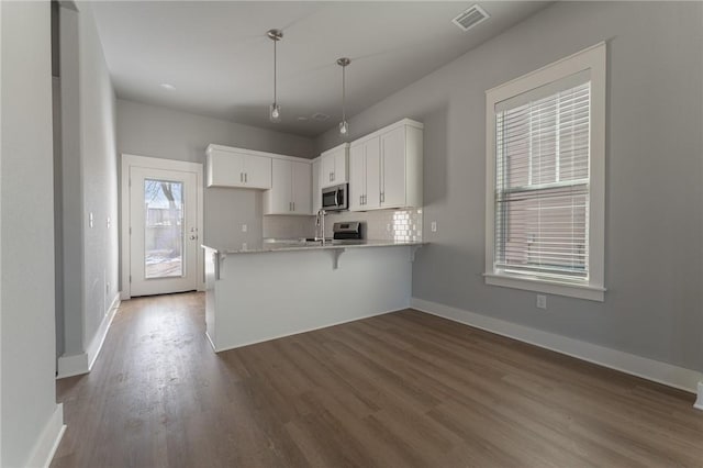 kitchen featuring white cabinetry, kitchen peninsula, stainless steel appliances, tasteful backsplash, and pendant lighting