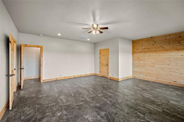 spare room featuring ceiling fan and wooden walls