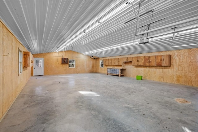 garage featuring a garage door opener, wood walls, and electric panel