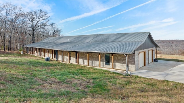 view of front facade with a front lawn, central air condition unit, covered porch, and a garage