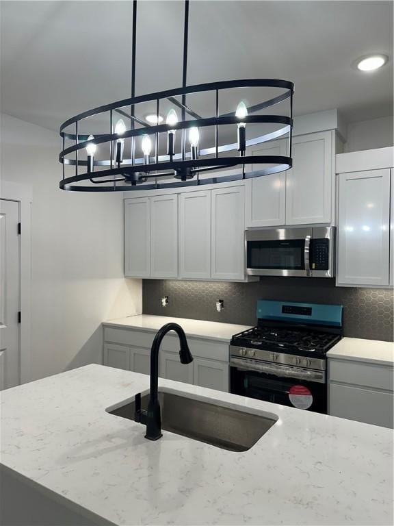 kitchen with light stone countertops, appliances with stainless steel finishes, white cabinets, and sink