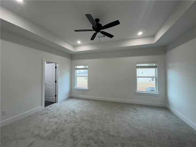 unfurnished room featuring a raised ceiling, ceiling fan, and carpet floors