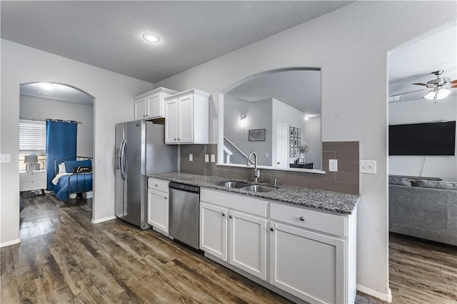 kitchen with stone counters, stainless steel appliances, dark wood-style flooring, a sink, and white cabinets