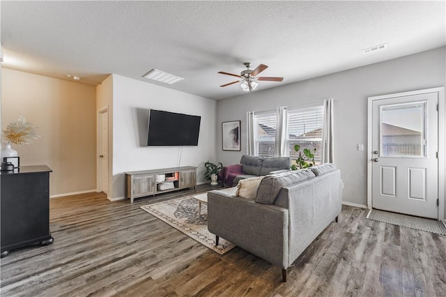 living area featuring a textured ceiling, wood finished floors, visible vents, and a ceiling fan