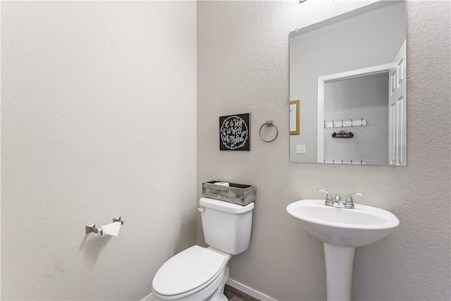 bathroom featuring toilet and baseboards