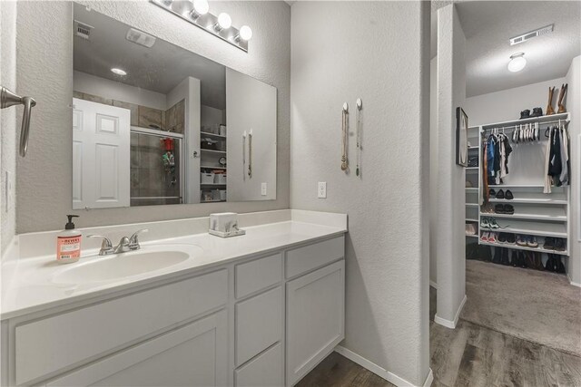 bathroom with a shower with shower door, vanity, and hardwood / wood-style flooring