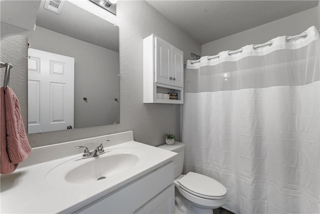 bathroom with toilet, vanity, and a textured ceiling