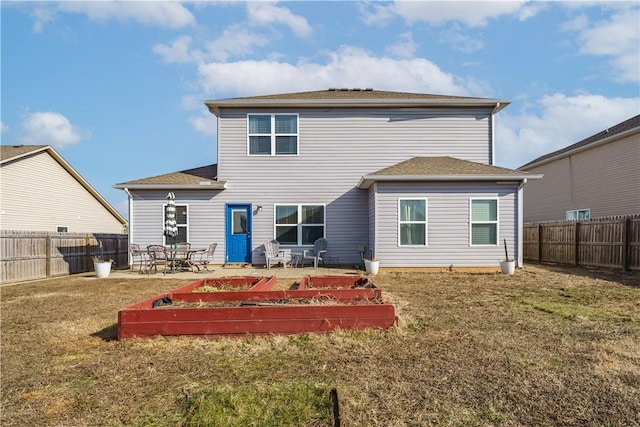 back of property with a garden, a yard, and a fenced backyard