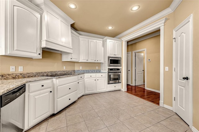 kitchen featuring crown molding, light stone counters, stainless steel appliances, and white cabinetry