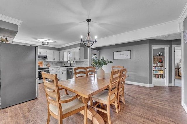 dining room featuring sink, wood-type flooring, crown molding, and a notable chandelier