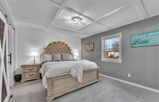 carpeted bedroom featuring a barn door and coffered ceiling