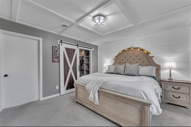 bedroom featuring a barn door, coffered ceiling, a closet, light colored carpet, and a walk in closet