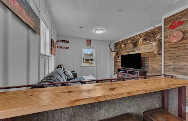 living room featuring a textured ceiling and wood walls