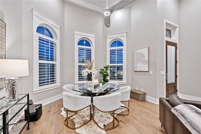 dining space with light hardwood / wood-style flooring and a towering ceiling