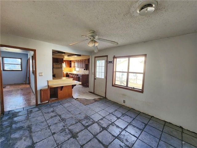 kitchen featuring a textured ceiling, ceiling fan, and refrigerator