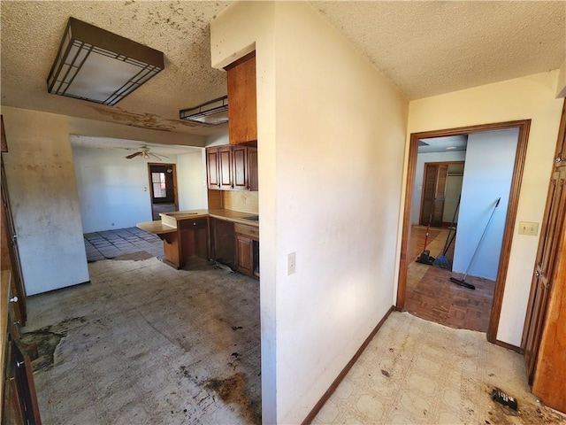 kitchen featuring ceiling fan, kitchen peninsula, and a textured ceiling