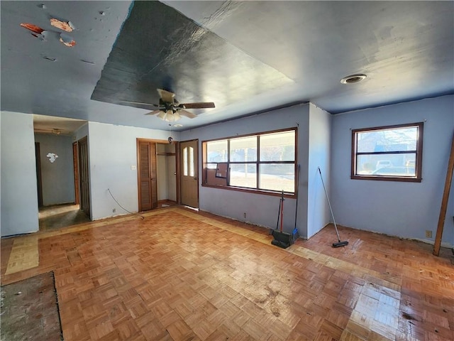 interior space featuring ceiling fan, parquet flooring, and a wealth of natural light