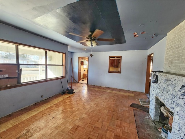 unfurnished living room featuring ceiling fan, light parquet flooring, and a fireplace