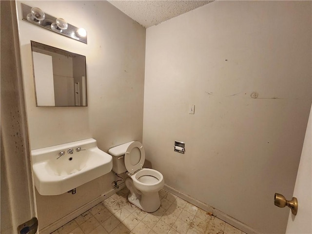 bathroom featuring toilet, sink, and a textured ceiling