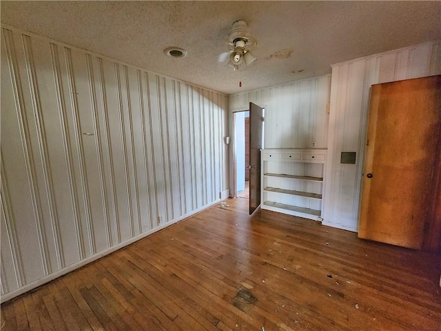 spare room featuring ceiling fan, wood-type flooring, and a textured ceiling