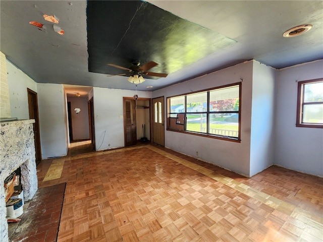 unfurnished living room featuring a ceiling fan and a fireplace