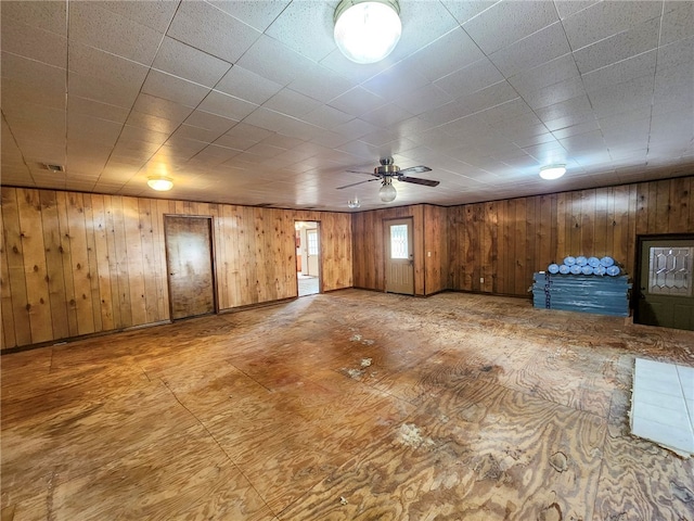 below grade area with ceiling fan, visible vents, and wooden walls