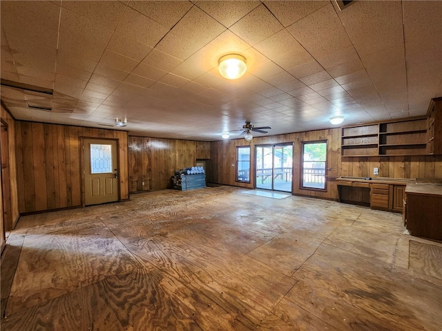 unfurnished living room with wood walls and a ceiling fan