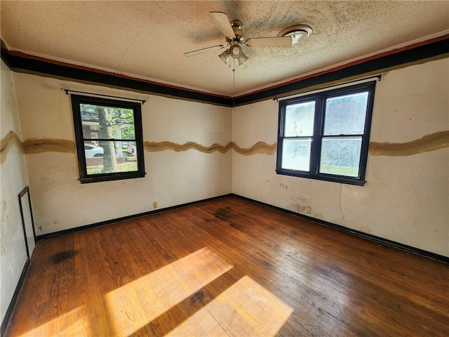 spare room featuring hardwood / wood-style flooring, a wealth of natural light, a ceiling fan, and a textured ceiling