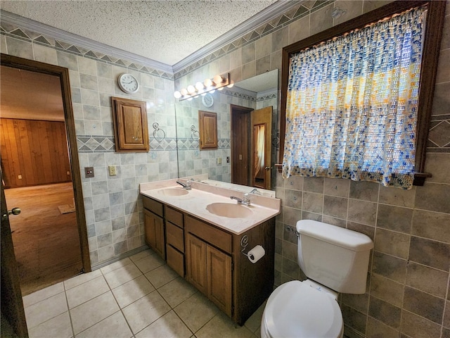 full bath with tile walls, tile patterned flooring, toilet, and a sink