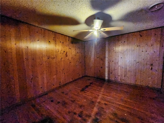 unfurnished room featuring wood walls, a ceiling fan, and wood finished floors