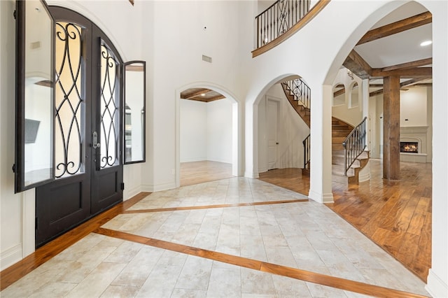 foyer entrance featuring wood-type flooring, french doors, and beamed ceiling