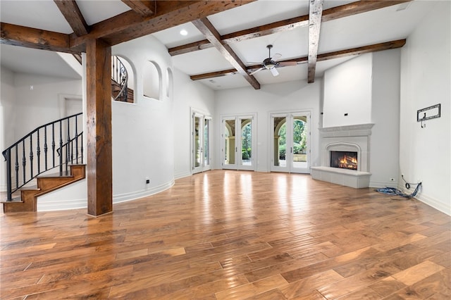 unfurnished living room featuring ceiling fan, light wood-type flooring, beamed ceiling, and a fireplace