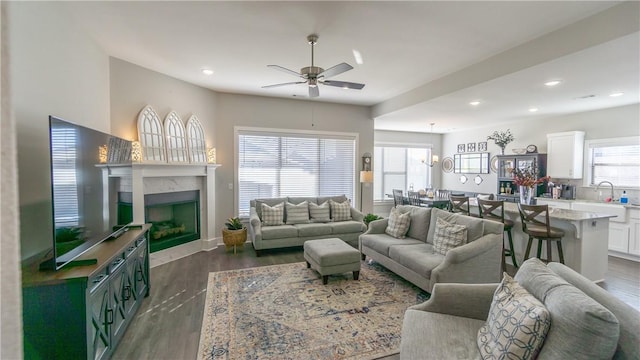 living room featuring a fireplace, plenty of natural light, dark hardwood / wood-style floors, and ceiling fan