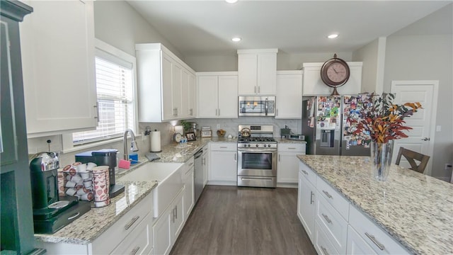 kitchen with dark wood-type flooring, appliances with stainless steel finishes, white cabinetry, light stone countertops, and decorative backsplash