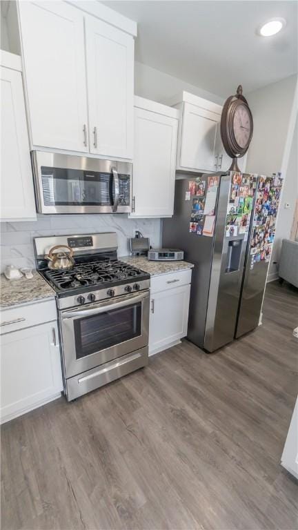 kitchen with light stone counters, wood-type flooring, white cabinets, and appliances with stainless steel finishes