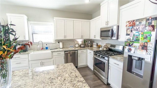 kitchen featuring sink, dark wood-type flooring, appliances with stainless steel finishes, white cabinetry, and light stone countertops