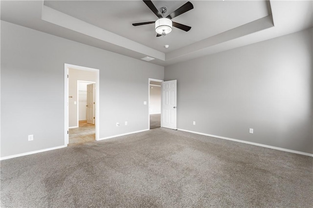 unfurnished bedroom featuring ceiling fan, light colored carpet, and a tray ceiling