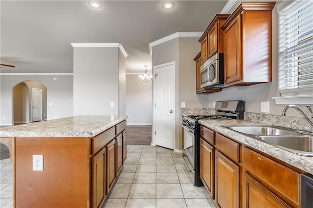 kitchen with stainless steel appliances, a kitchen island, light tile patterned flooring, ornamental molding, and sink