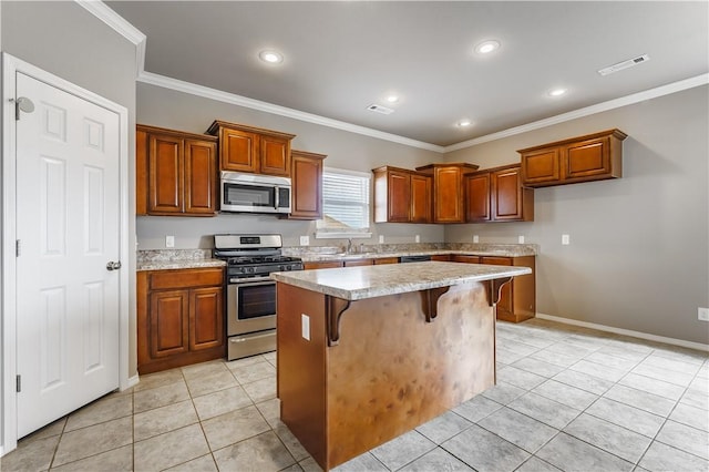 kitchen featuring a kitchen breakfast bar, appliances with stainless steel finishes, crown molding, and a kitchen island