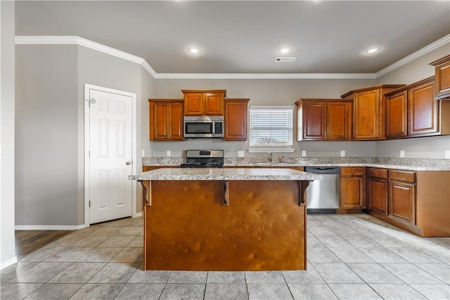 kitchen with a kitchen island, light stone countertops, appliances with stainless steel finishes, a kitchen breakfast bar, and ornamental molding