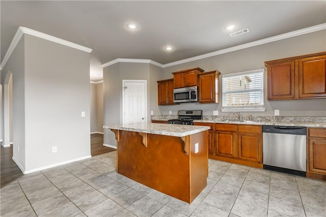 kitchen with appliances with stainless steel finishes, a kitchen island, sink, a kitchen breakfast bar, and ornamental molding