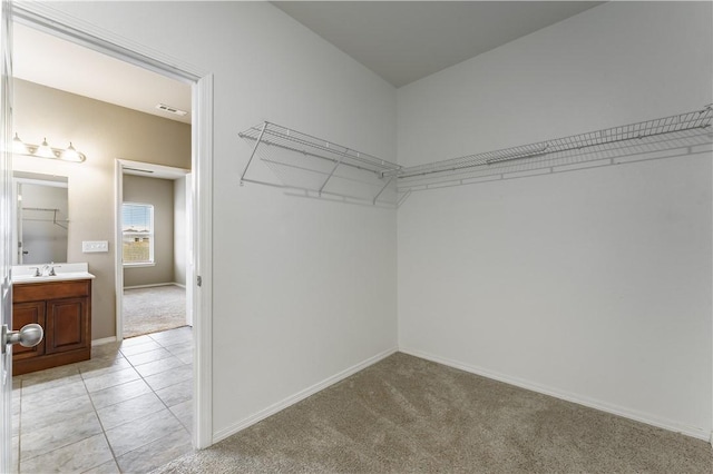 walk in closet with light carpet and sink