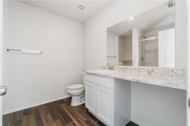 bathroom with vanity, toilet, hardwood / wood-style floors, and a shower with door