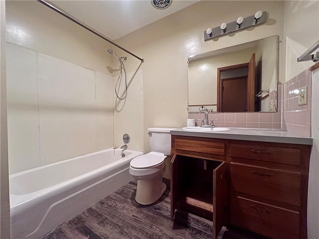 full bathroom with washtub / shower combination, vanity, tasteful backsplash, wood-type flooring, and toilet