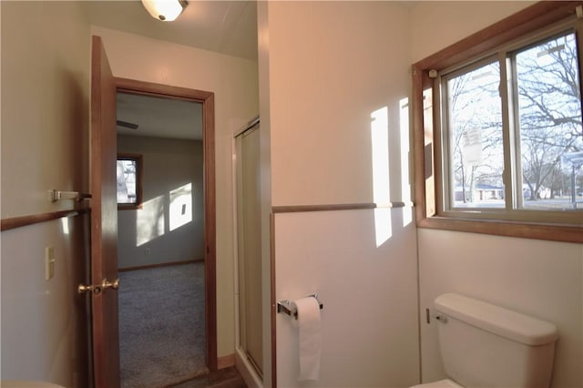 bathroom featuring a shower with door and toilet