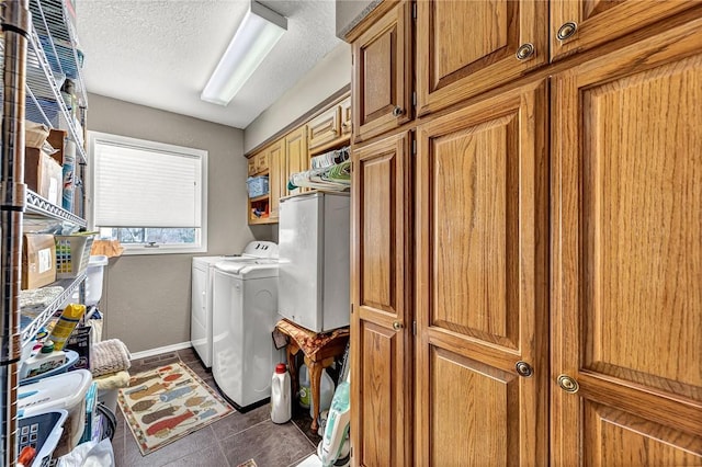 laundry area featuring cabinets, a textured ceiling, separate washer and dryer, and dark tile patterned floors