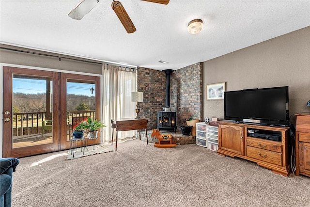 living room featuring a wood stove, carpet flooring, and a textured ceiling